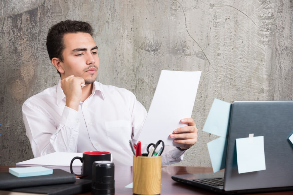 Jovem à mesa do escritório analisando carta de crédito.