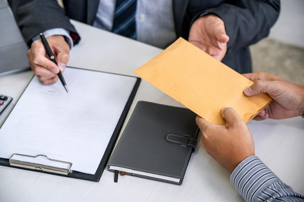 Duas pessoas à mesa do escritório conferindo documentos para assinatura